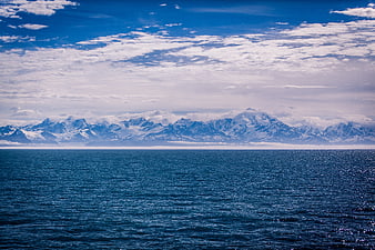 Snowy mountain range across deep blue ocean water