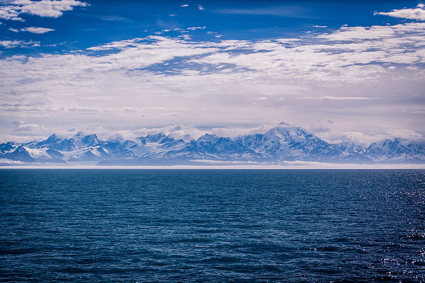 Snowy mountain range across deep blue ocean water