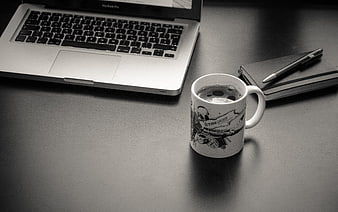 Black and white workspace with laptop, coffee mug, and notebook