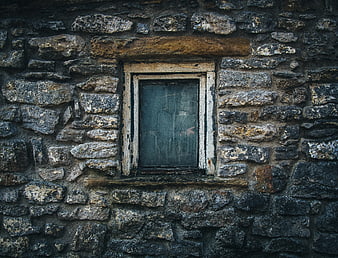 Old rustic stone wall with weathered wooden window