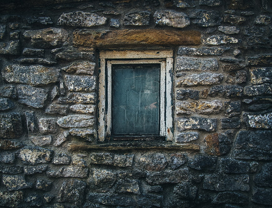 Old rustic stone wall with weathered wooden window