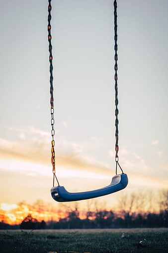 Empty blue swing set against a golden sunset sky