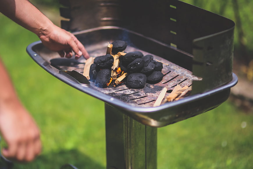 Person lighting charcoal grill outdoors