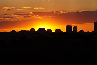 Silhouette of city skyline against vibrant orange sunset sky