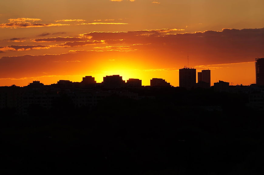 Silhouette of city skyline against vibrant orange sunset sky