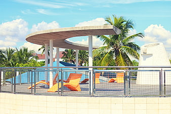 Modern tropical resort pool deck with orange lounge chairs