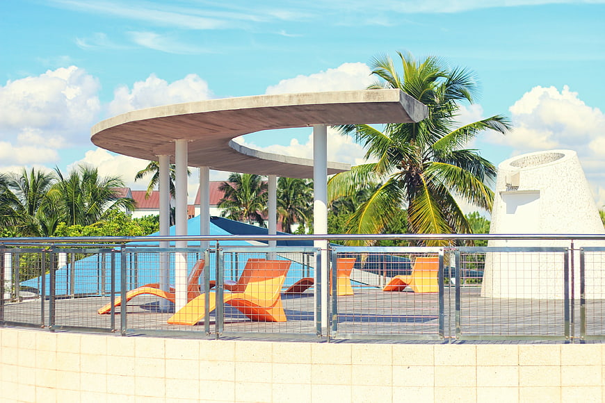 Modern tropical resort pool deck with orange lounge chairs