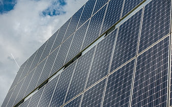Low angle view of solar panels against a cloudy blue sky
