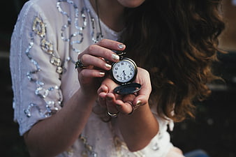 Woman holding vintage pocket watch with gold manicure