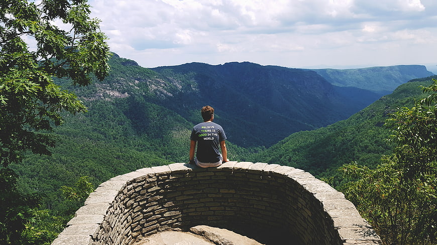 Man Sitting on Stone Wall Overlooking Mountain Valley