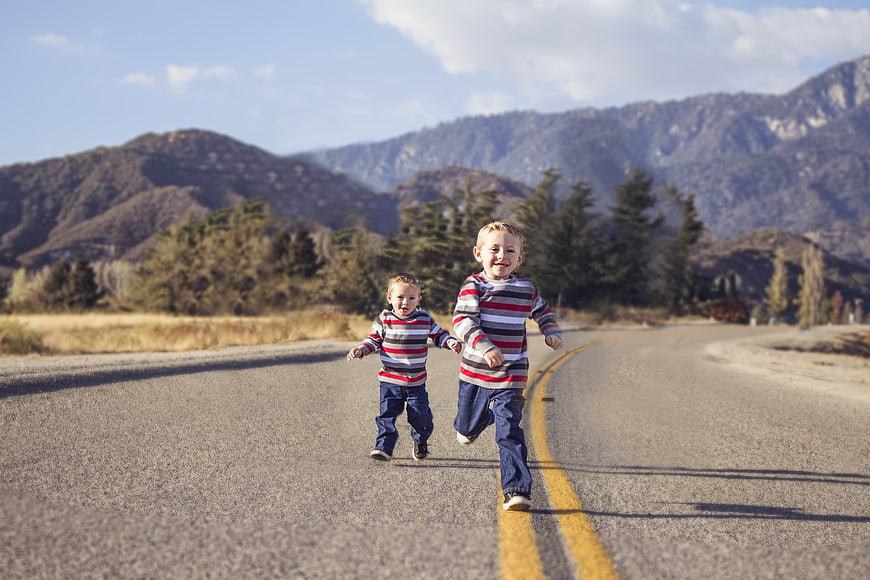 Two young boys running hand in hand on a country road