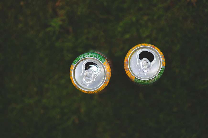Top View of Two Soda Cans on Green Grass