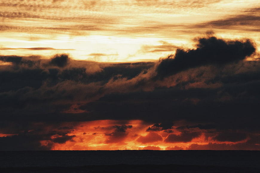 Dramatic sunset over ocean with dark clouds and golden light