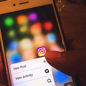 Close-up of finger tapping Instagram app on smartphone screen