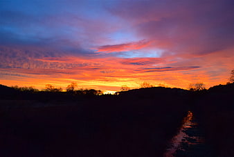 Vibrant Orange and Purple Sunset Sky Over Silhouetted Landscape