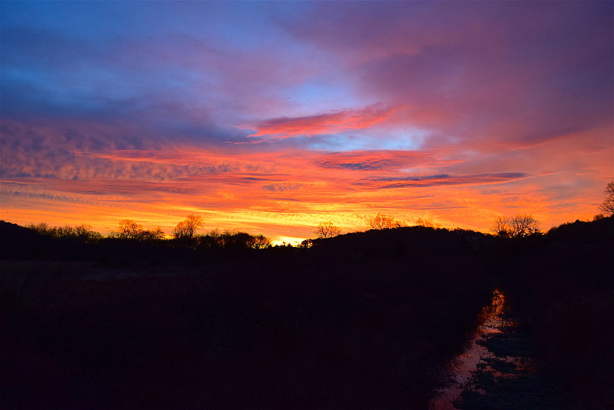 Vibrant Orange and Purple Sunset Sky Over Silhouetted Landscape