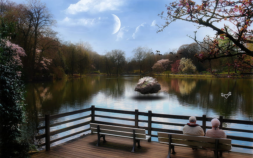 Senior couple sitting on park bench by lake with surreal floating rock