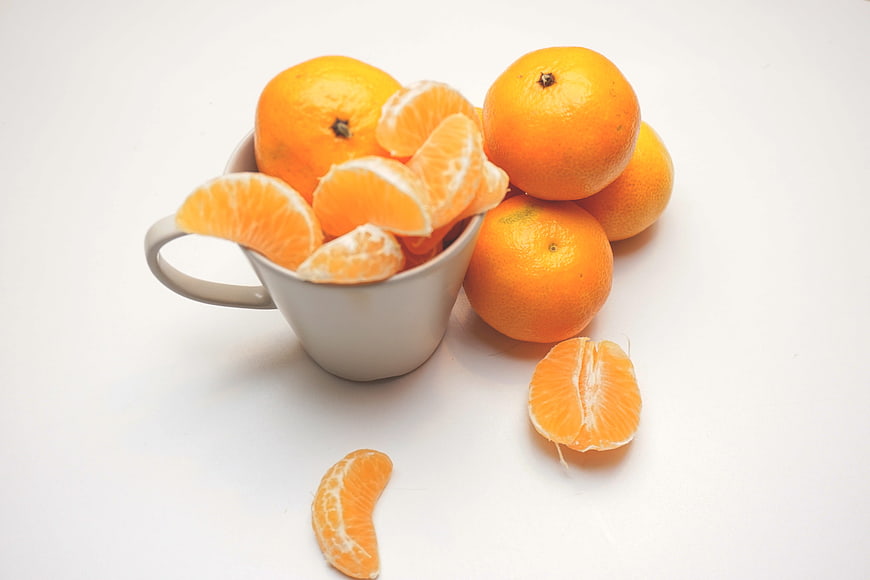 Fresh Oranges In White Ceramic Mug On White Background