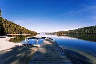 Wooden Dock Extending into Calm Blue Lake with Forest