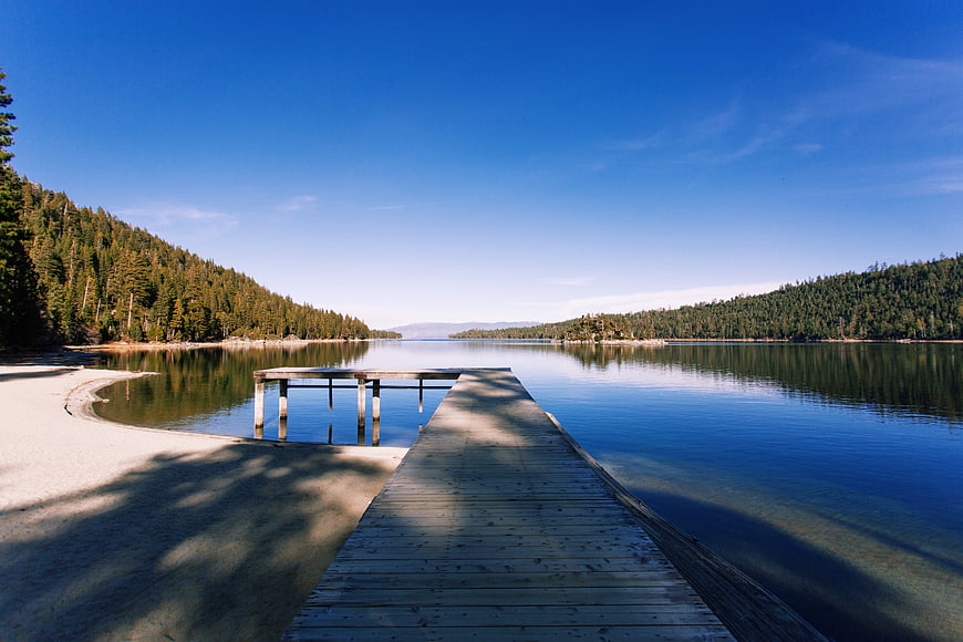 Wooden Dock Extending into Calm Blue Lake with Forest