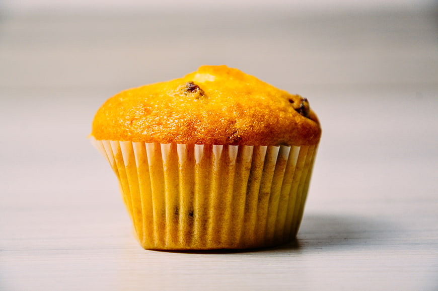Golden Muffin with Raisins on White Background