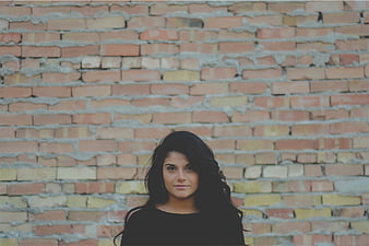 Portrait of young woman with dark hair against brick wall