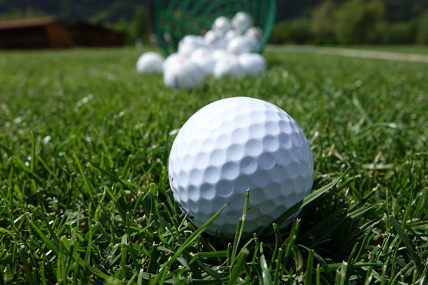 Close-up of white golf ball on green grass with basket
