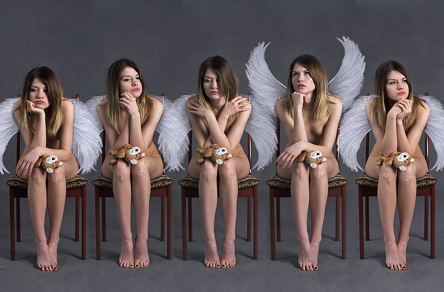 Five women with angel wings sitting on chairs in a row