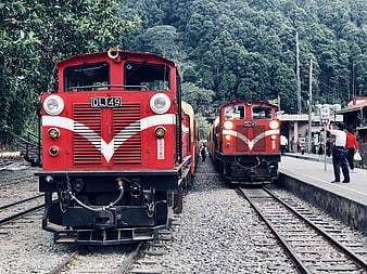 Two red diesel locomotives at a mountain railway station