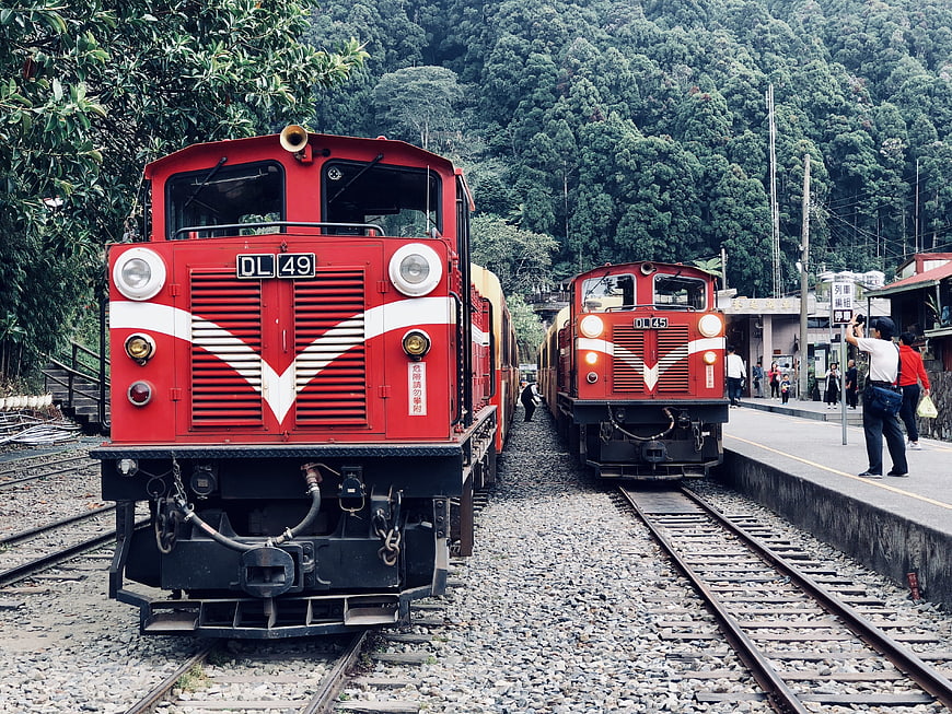 Two red diesel locomotives at a mountain railway station