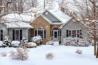Snow-Covered Gray House with Brick Accents in Winter