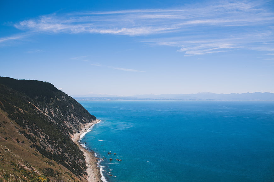 Aerial View of Rugged Coastline with Turquoise Sea and Blue Sky
