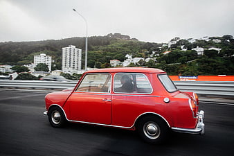 Vintage red Mini Cooper driving on a highway