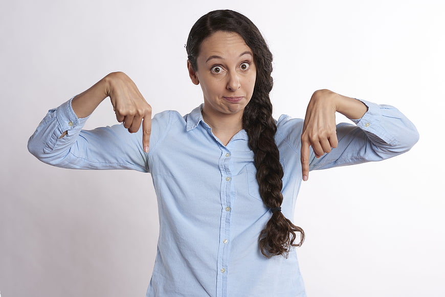 Woman Pointing Down with Surprised Expression on White Background