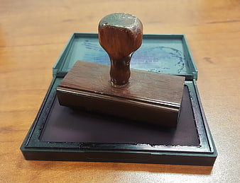 Wooden rubber stamp resting on open ink pad