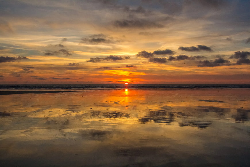 Serene Sunset Over Wet Sandy Beach with Reflections