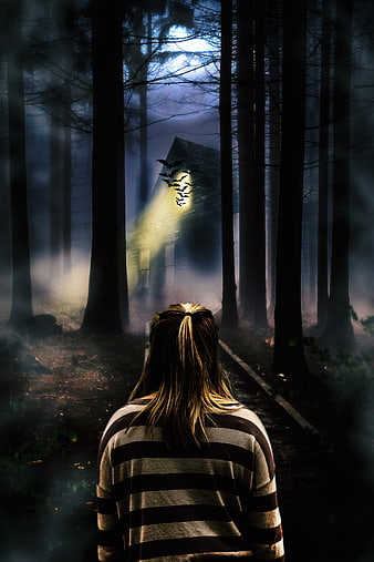 Woman walking toward haunted house in dark forest