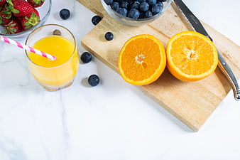 Fresh orange juice with strawberries and blueberries on marble