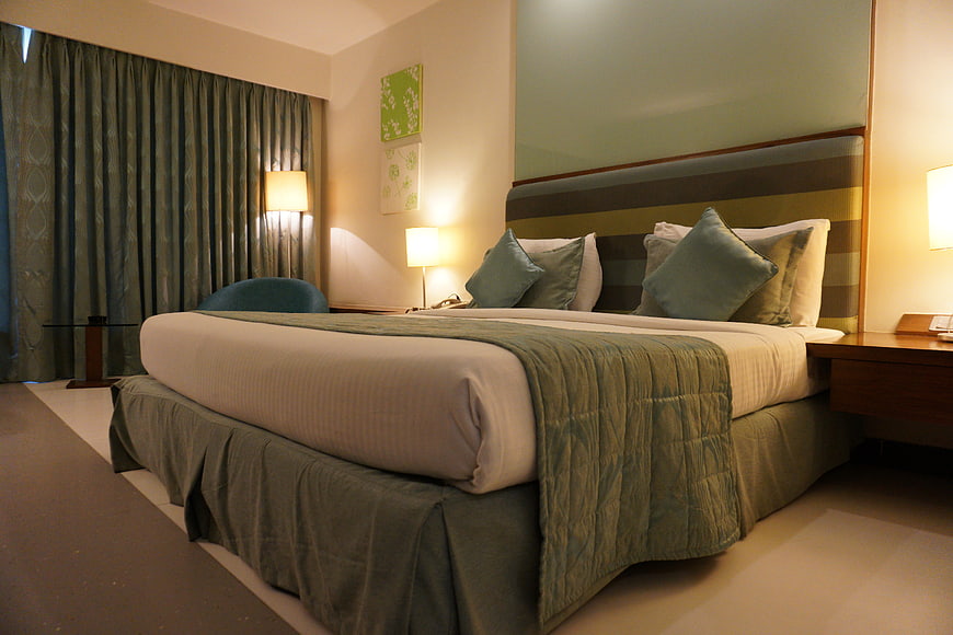 Modern Hotel Bedroom Interior with Green Bedding and Warm Lighting