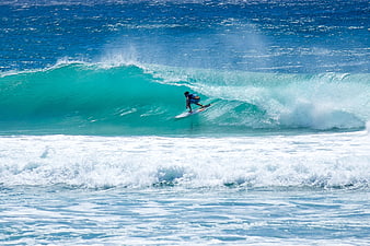 Surfer Riding Turquoise Wave in Deep Blue Ocean