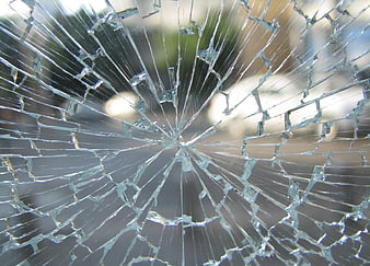 Close-up of shattered glass with radial cracks and blurred background
