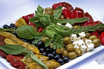 Mediterranean appetizer platter with olives, feta cheese, sun-dried tomatoes, and fresh herbs