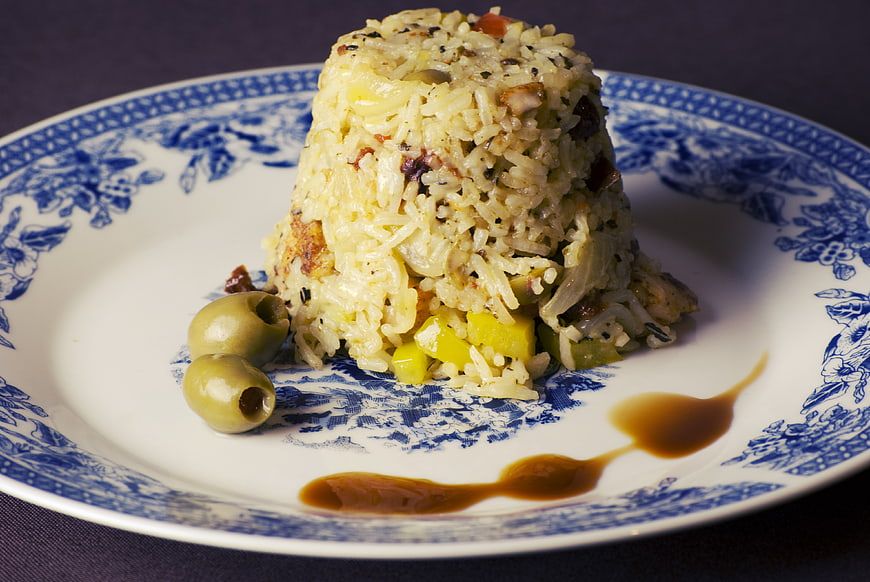 Molded fried rice with olives on blue and white plate