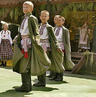 Young boys in traditional folk costumes performing a dance