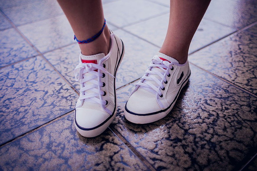 Close-up of white sneakers on tiled floor