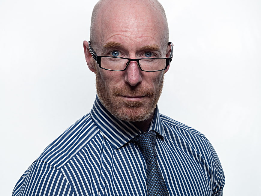 Professional Portrait of Bald Man With Glasses And Blue Striped Shirt