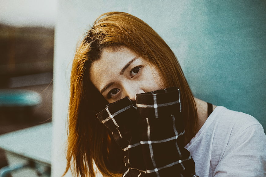Asian woman covering mouth with plaid sleeve