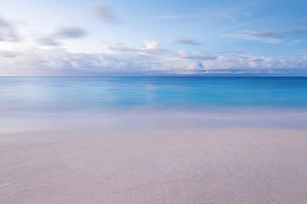 Serene Long Exposure Beach with Misty Ocean and Blue Sky