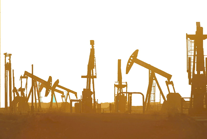 Silhouetted Oil Pumping Units In Desert At Golden Hour