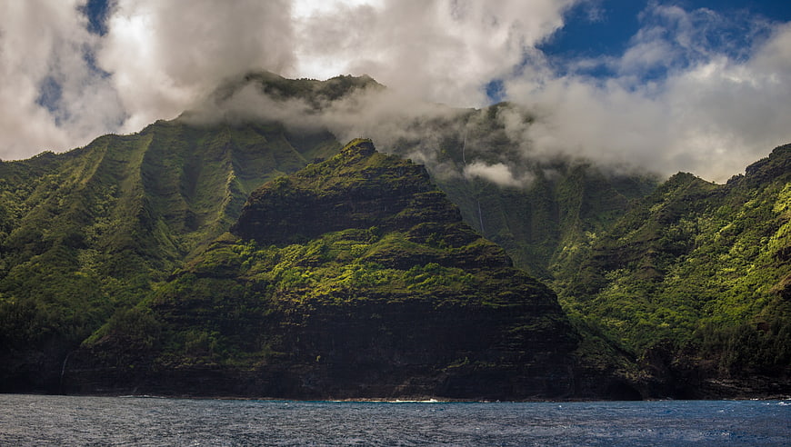 Dramatic Green Mountain Cliffs Rising from Ocean with Clouds